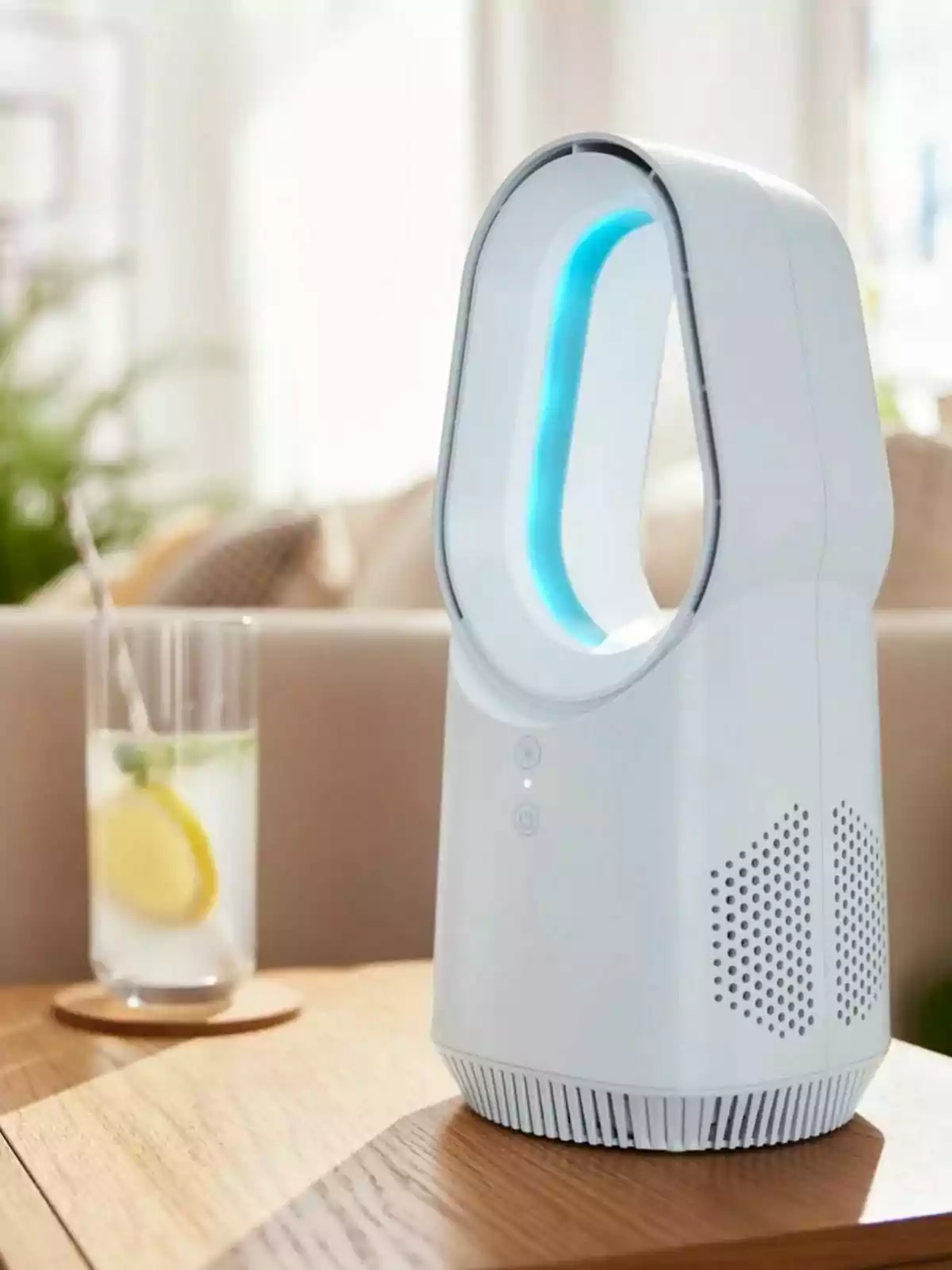 Ventilador sense aspes de color blanc de Lidl sobre una taula de fusta al costat d’un got amb aigua, rodanxes de llimona i una palleta, en un ambient il·luminat i modern.