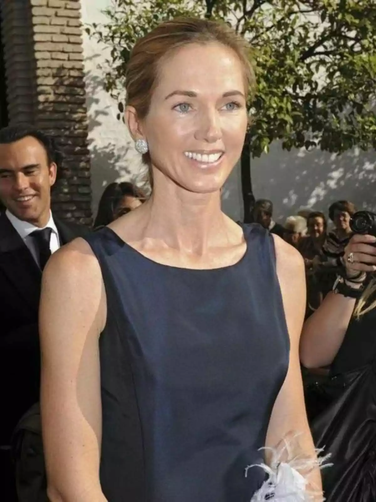 Miranda Rijnsburger smiling in a dark blue dress and sparkly earrings, surrounded by people at an outdoor event. Miranda Rijnsburger smiling in a dark blue dress and sparkly earrings, surrounded by people at an outdoor event.