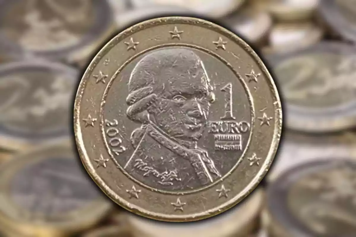 Imatge de fons de diverses monedes de 2 i 1 euro difuminades i una altra imatge d'una moneda de 2 euros amb la imatge d'Amadeus Mozart i de l'any 2002