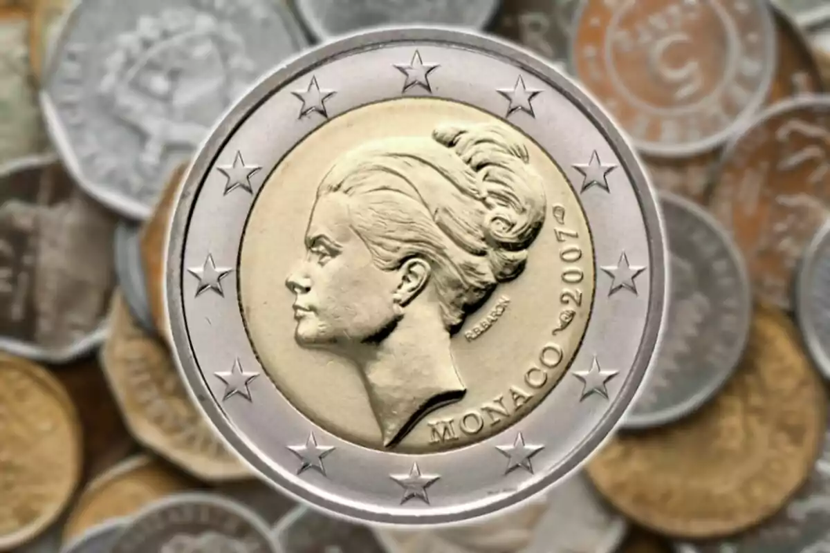 Una moneda de 2 euros de Mònaco de l'any 2007 amb la imatge d'una dona a l'anvers i diverses monedes desenfocades al fons.