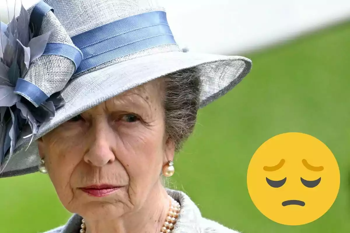 Anna de Regne Unit amb barret elegant i expressió seriosa, acompanyada d'un emoji de cara trista.