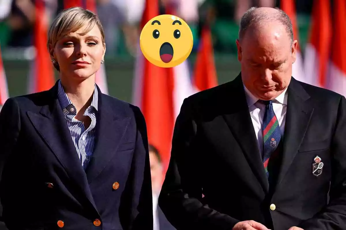 Charlene i Alberto de Monaco vestits formalment estan drets una al costat de l'altra amb un emoji sorprès sobre ells i banderes de fons.