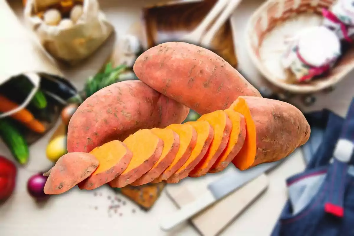 Muntatge amb un taulell de cuina plena d'aliments i utensilis de fons i, al centre, dos moniatos sencers i un tallat a rodanxes