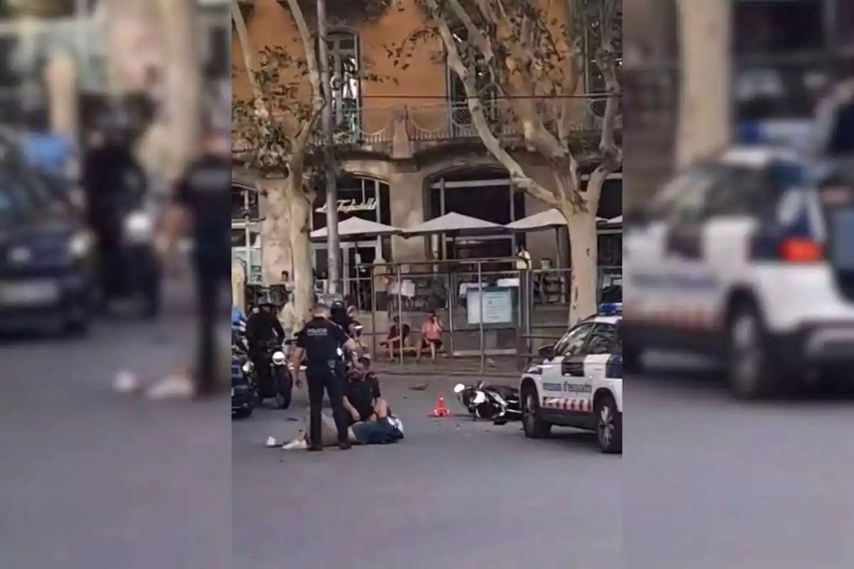 Muntatge amb la captura del moment de l'accident del motorista estirat a terra amb els Mossos atenent-lo a Barcelona