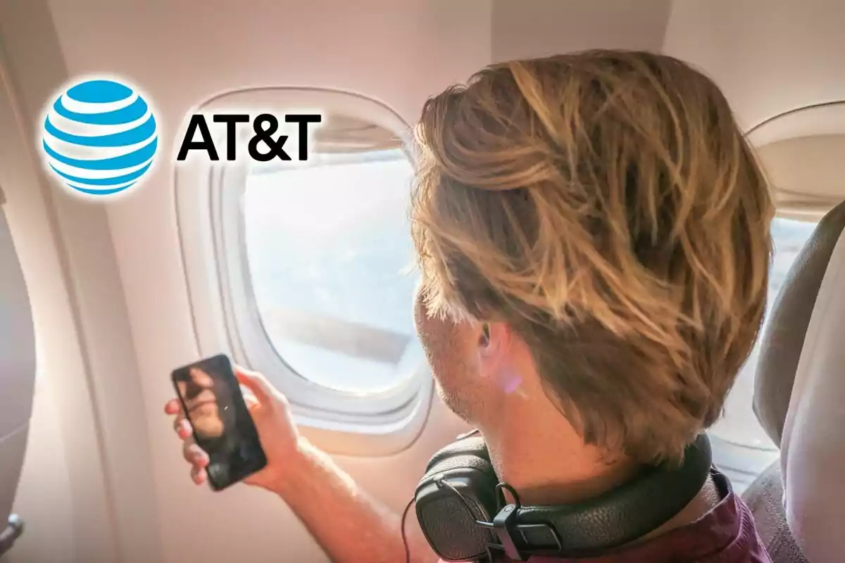 A man sitting on a plane looking out the window while holding a mobile phone, with headphones around his neck and the AT&T logo in the top left corner. A man sitting on a plane looking out the window while holding a mobile phone, with headphones around his neck and the AT&T logo in the top left corner.