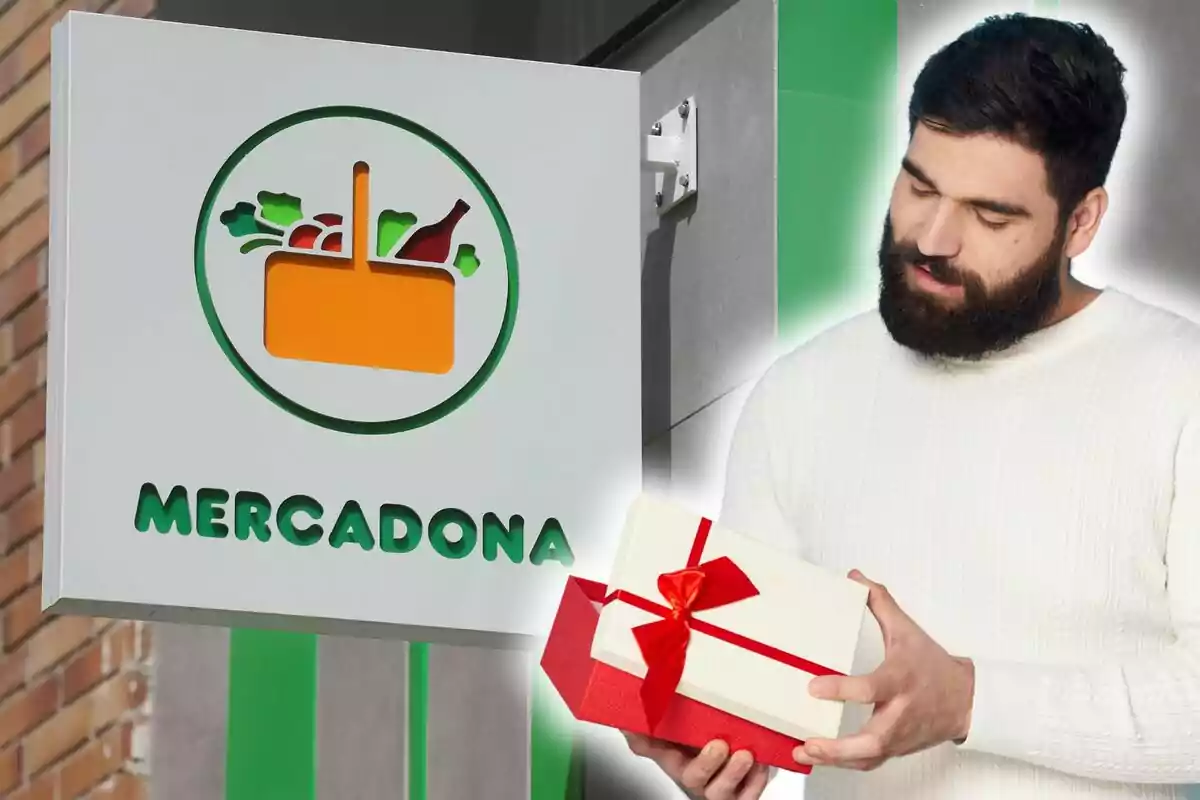 Un home amb barba i jersei blanc sosté una caixa de regal amb un llaç vermell davant d'un cartell d'una botiga amb el logotip d'una cistella de la compra i el nom "Mercadona".