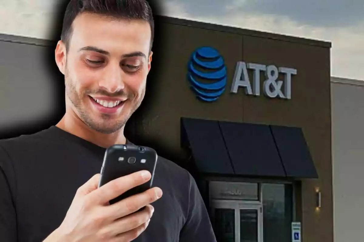 Un hombre sonriente mira su teléfono frente a una tienda de AT&T.