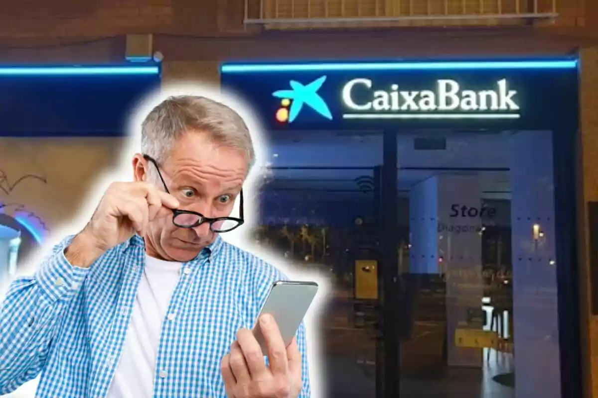 Home gran mirant el telèfon mòbil amb expressió de sorpresa davant d'una sucursal de CaixaBank.