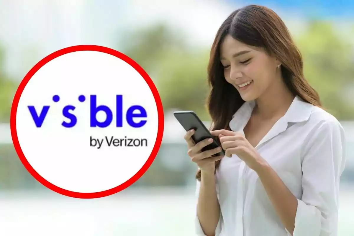A smiling woman in a white jersey uses her mobile phone while the A smiling woman in a white jersey uses her mobile phone while the