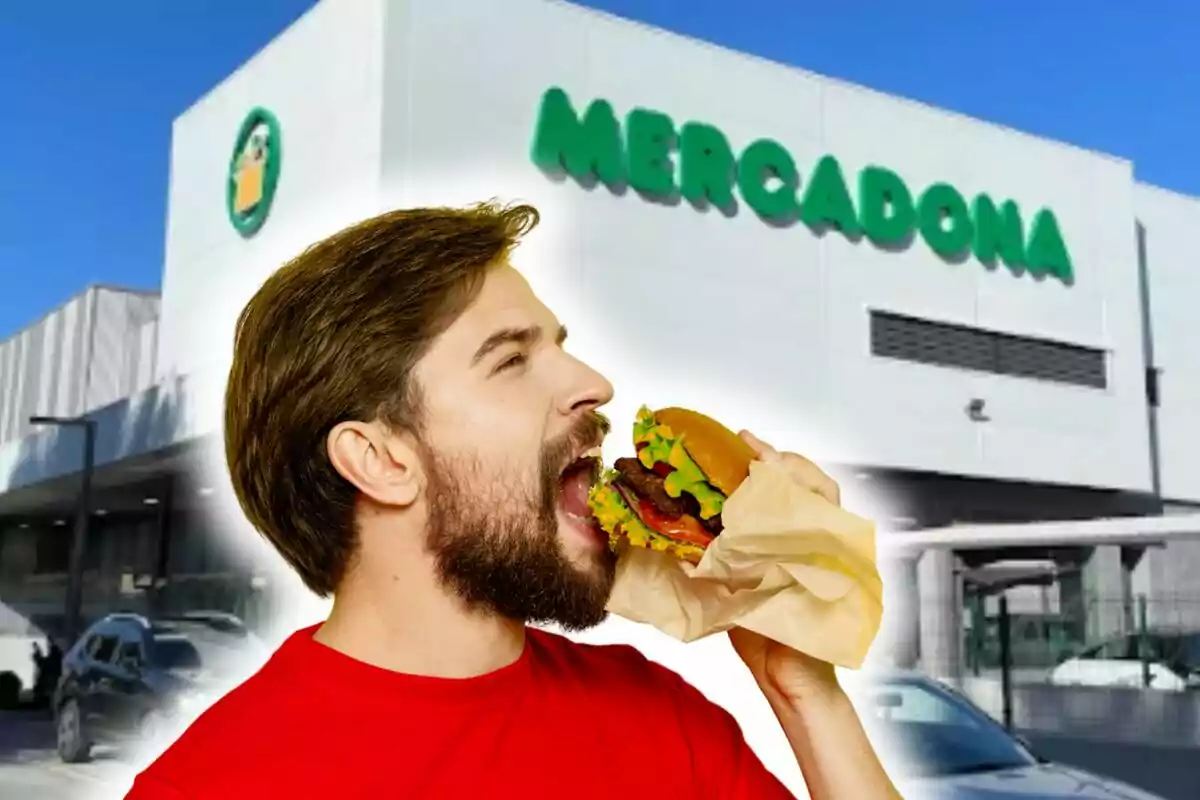 Un home amb barba i samarreta vermella està a punt de mossegar una hamburguesa davant d'un edifici amb el rètol de "Mercadona".