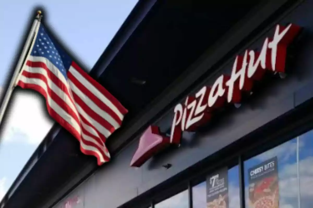 Facade of a Pizza Hut restaurant with a United States flag waving beside it.
