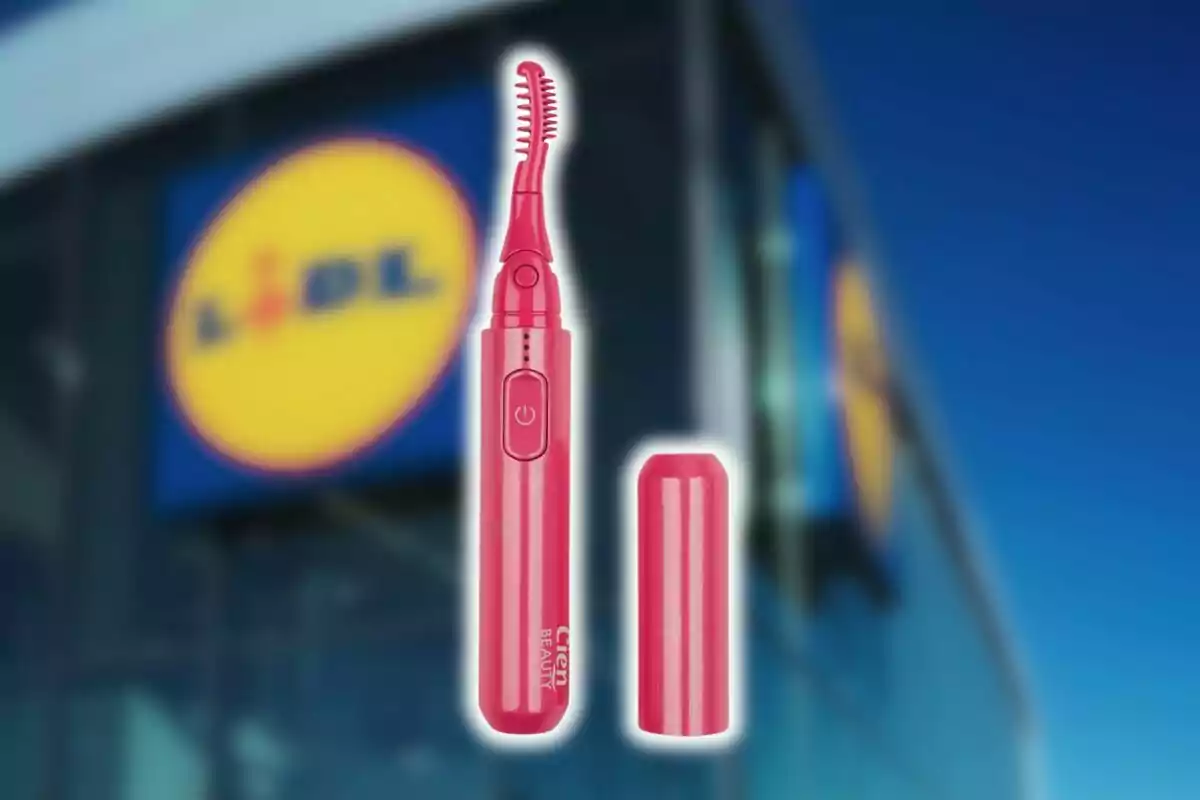 Arrissador de pestanyes elèctric de color rosa de Lidl amb tapa al costat de la façana d’una botiga Lidl desenfocada al fons. Arrissador de pestanyes elèctric de color rosa de Lidl amb tapa al costat de la façana d’una botiga Lidl desenfocada al fons.