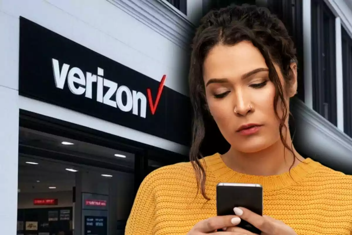 A person in a yellow sweater using a phone in front of a Verizon store.