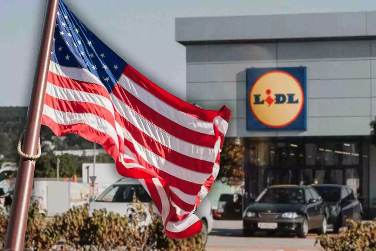 Bandera de Estados Unidos ondeando frente a una tienda Lidl con coches estacionados Bandera de Estados Unidos ondeando frente a una tienda Lidl con coches estacionados