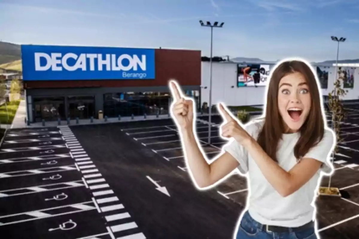 Una dona somrient assenyala cap a un edifici de Decathlon amb un estacionament buit en primer pla.