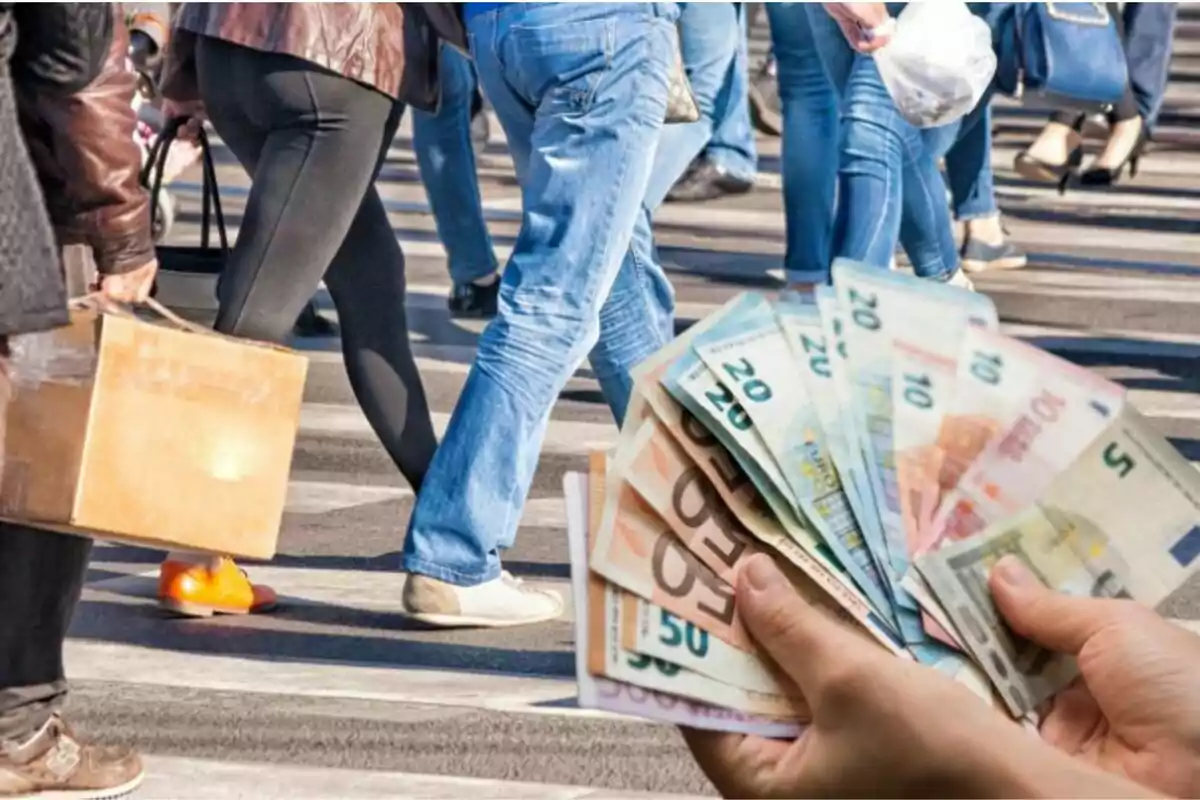 Persones caminant al carrer mentre algú sosté diversos bitllets en primer pla.