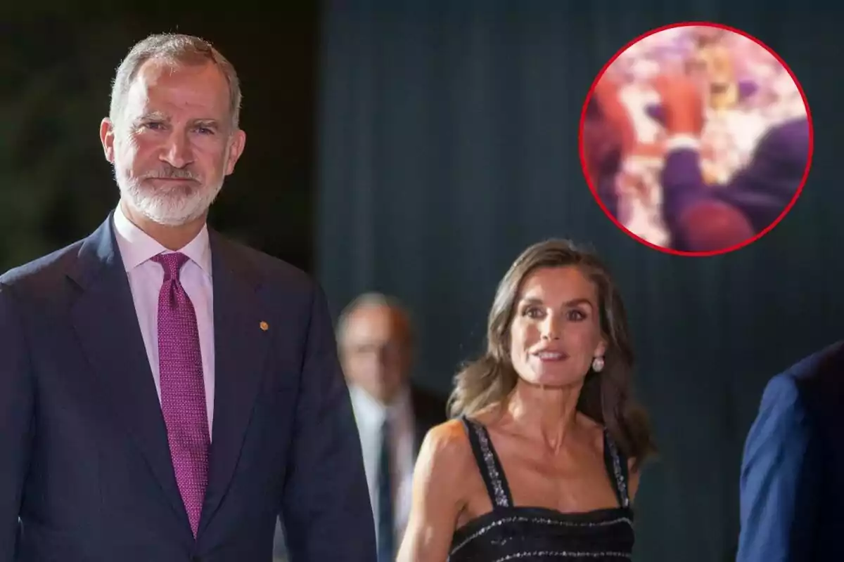 Felip VI i Letizia elegantment vestida camina en un esdeveniment nocturn amb un fons fosc i un cercle vermell que destaca una imatge borrosa a la cantonada superior dreta.