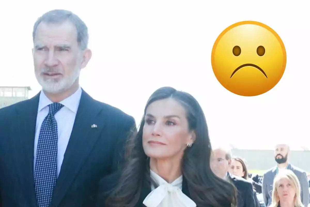 Felip VI i la reina Letícia vestida formalment està dreta a l'aire lliure amb un emoji de cara trista superposat a la cantonada superior dreta.