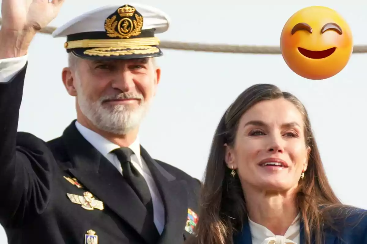Felip VI i la reina Letícia somrient, amb l'home vestit d'uniforme naval i una dona al seu costat, acompanyats d'un emoji somrient.