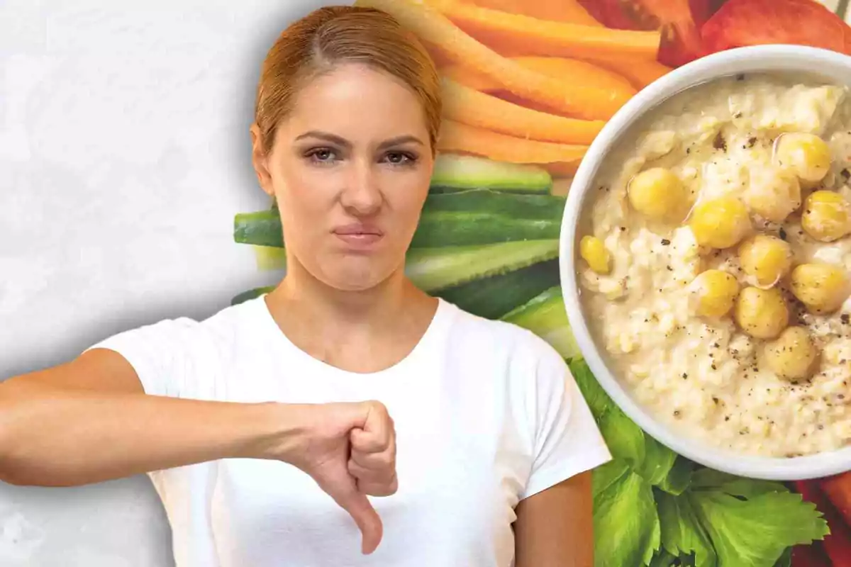 Dona amb expressió de desgrat mostrant el polze cap avall davant d'un plat d'hummus i vegetals.
