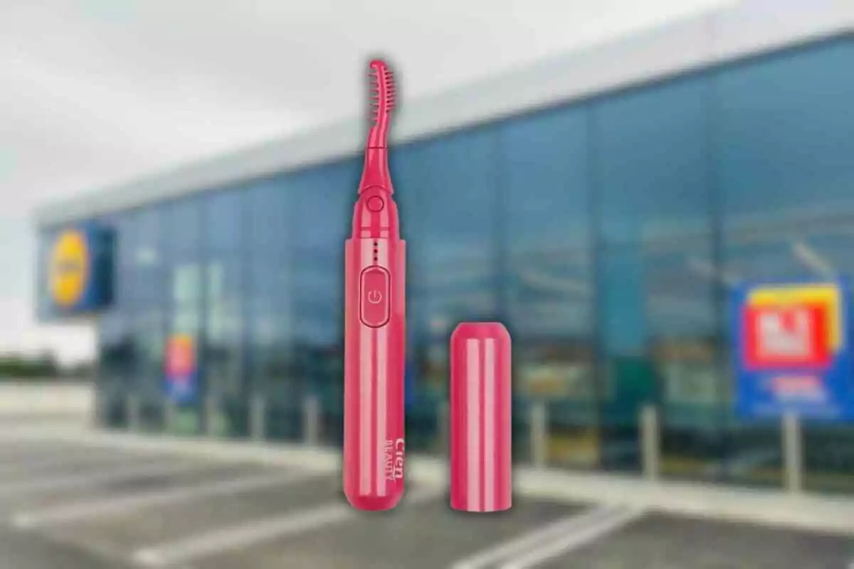 Arrissador de pestanyes elèctric de color rosa davant d’una botiga amb façana de vidre Arrissador de pestanyes elèctric de color rosa davant d’una botiga amb façana de vidre