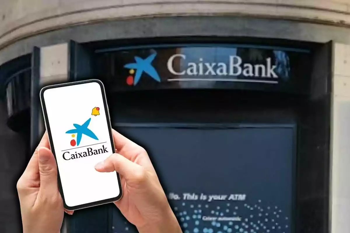 Una persona sosté un telèfon mòbil que mostra el logotip de CaixaBank davant d'una sucursal del banc.