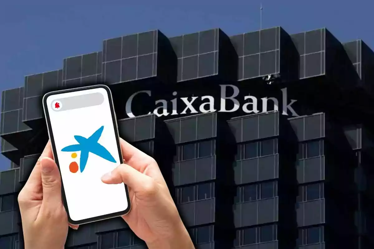 Persona sostenint un telèfon mòbil amb el logotip de CaixaBank davant d'un edifici de la mateixa entitat bancària.