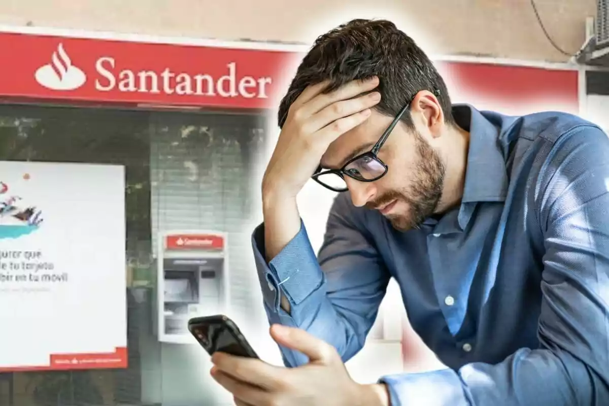 Home preocupat mirant el telèfon davant una sucursal del Banco Santander.