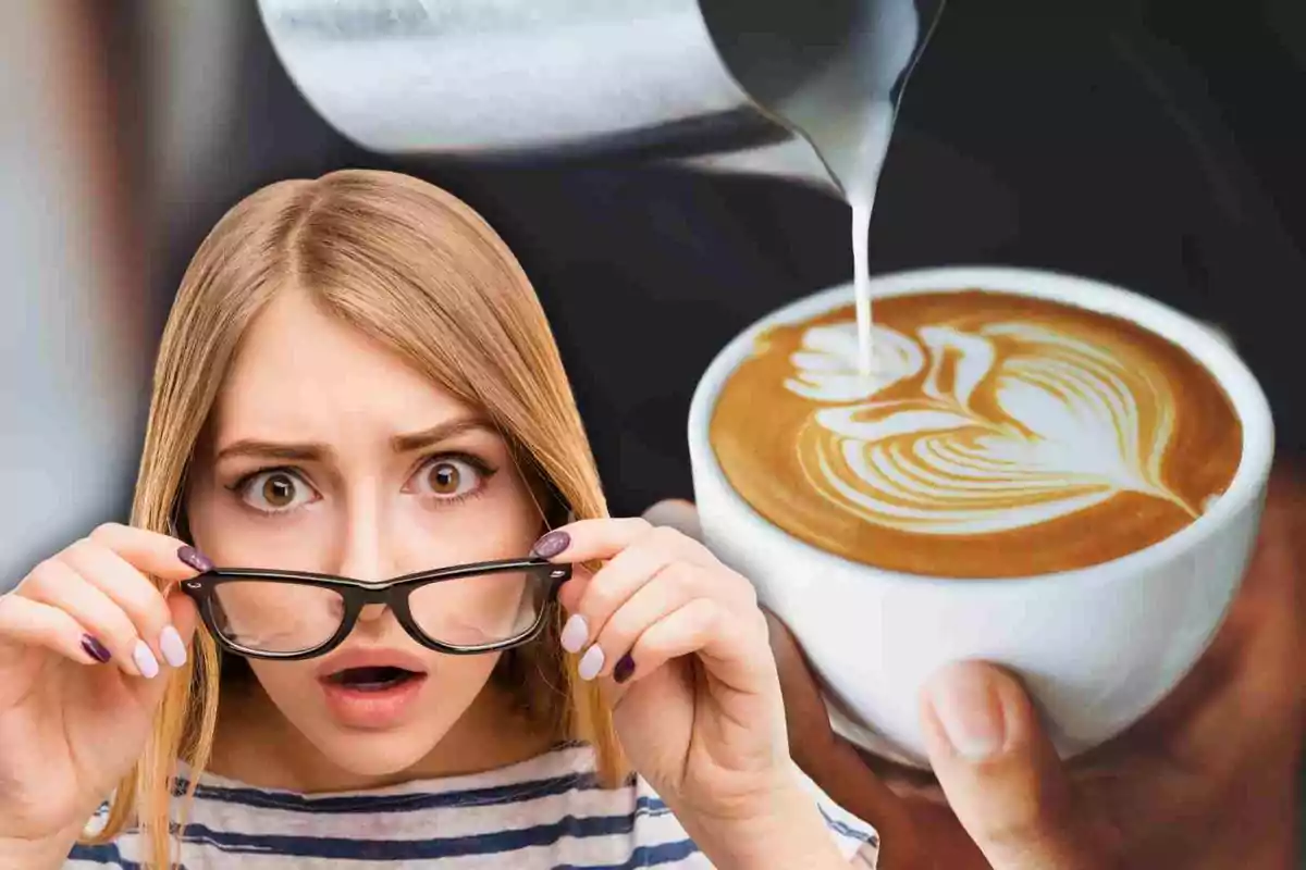 Una dona amb expressió de sorpresa sosté les seves ulleres mentre observa una tassa de cafè amb art latte.
