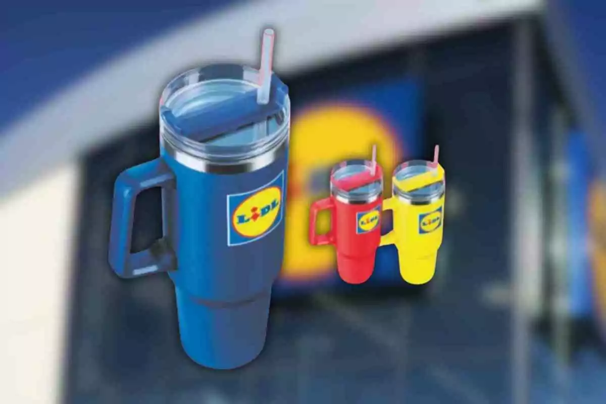 Tres gots tèrmics de colors blau, vermell i groc amb tapa i canyeta, cadascun amb el logotip de Lidl, sobre un fons desenfocat d’una botiga Tres gots tèrmics de colors blau, vermell i groc amb tapa i canyeta, cadascun amb el logotip de Lidl, sobre un fons desenfocat d’una botiga
