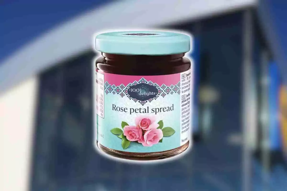 Frasco de mermelada de pétalos de rosa con tapa celeste y etiqueta decorada con rosas rosas sobre un fondo desenfocado. Frasco de mermelada de pétalos de rosa con tapa celeste y etiqueta decorada con rosas rosas sobre un fondo desenfocado.