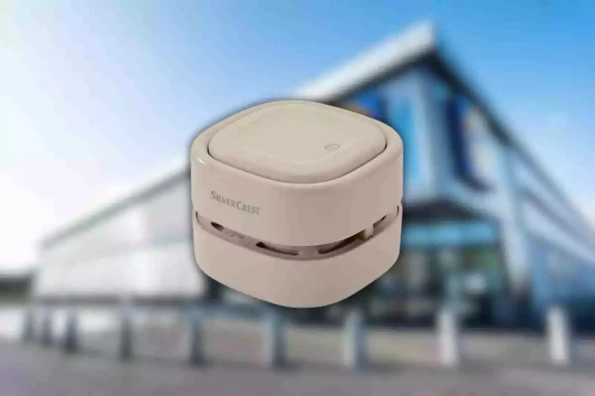 A small, square, beige device with the SilverCrest brand on a blurred background of a modern building. A small, square, beige device with the SilverCrest brand on a blurred background of a modern building.