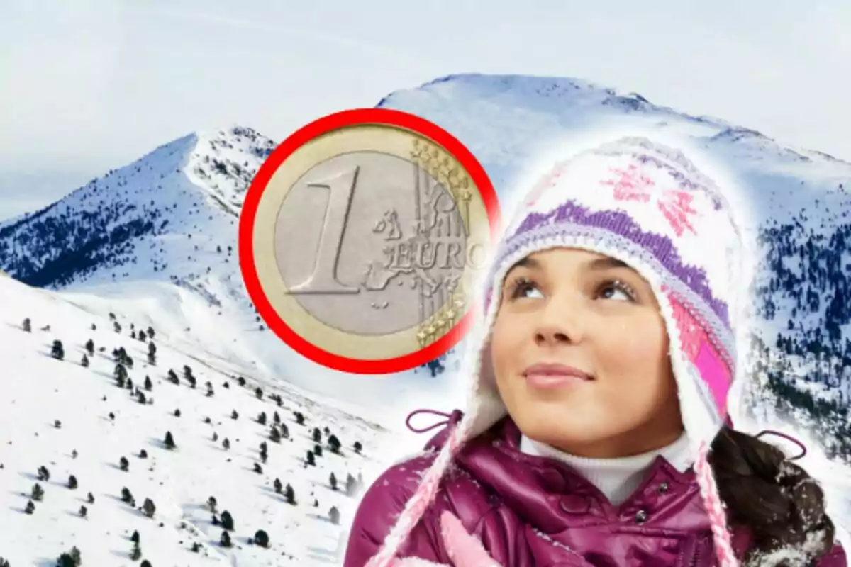 Una nena amb gorra d?hivern mira cap amunt amb una moneda d?un euro sobre un fons de muntanyes nevades a Andorra.