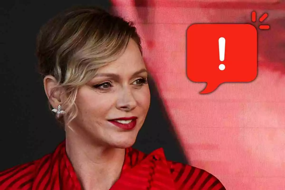 Charlene of Monaco with red lips and a red blouse looking to the right with a red speech bubble warning icon next to her