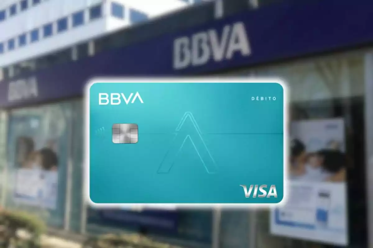 Tarjeta de débito BBVA Visa sobre fondo de sucursal bancaria.