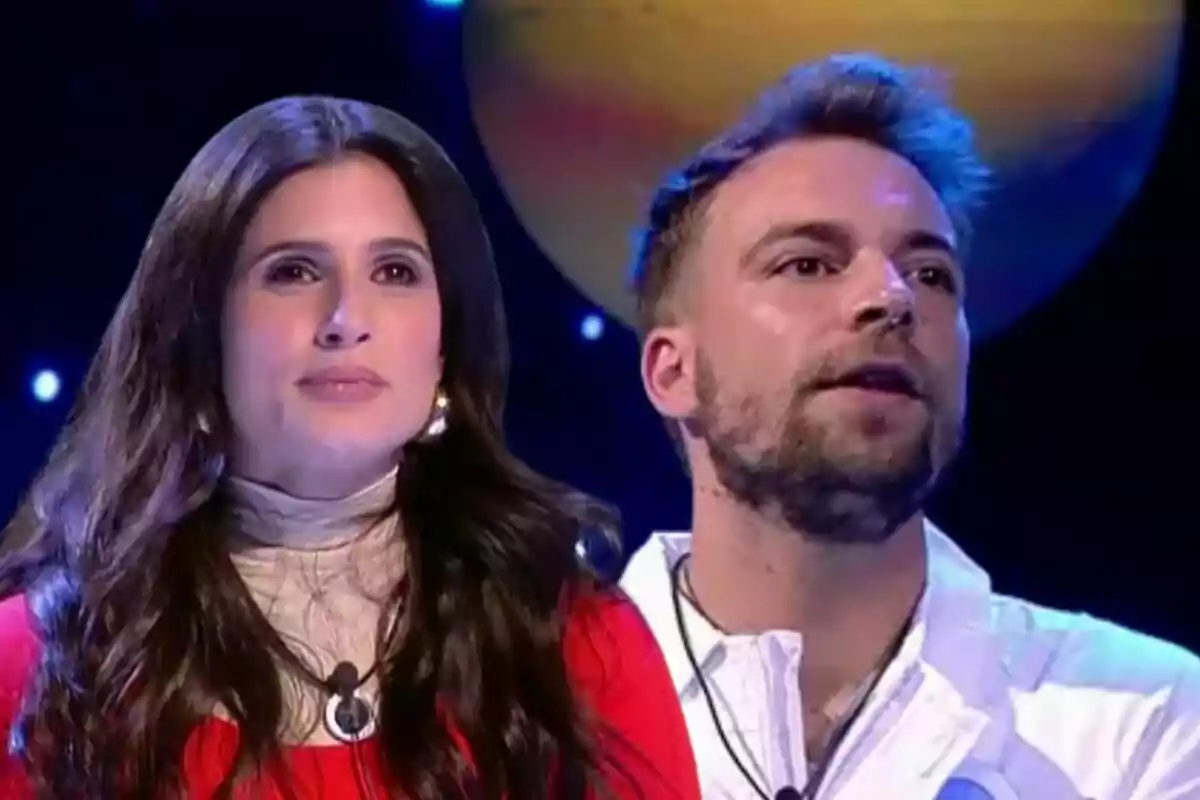 María Sánchez i José María Almoguera en un plató de televisió amb un fons fosc i un planeta il·luminat darrere. María Sánchez i José María Almoguera en un plató de televisió amb un fons fosc i un planeta il·luminat darrere.