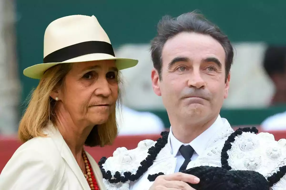 La infanta Elena amb barret i Enrique Ponce vestit de torero estan junts en un entorn exterior.