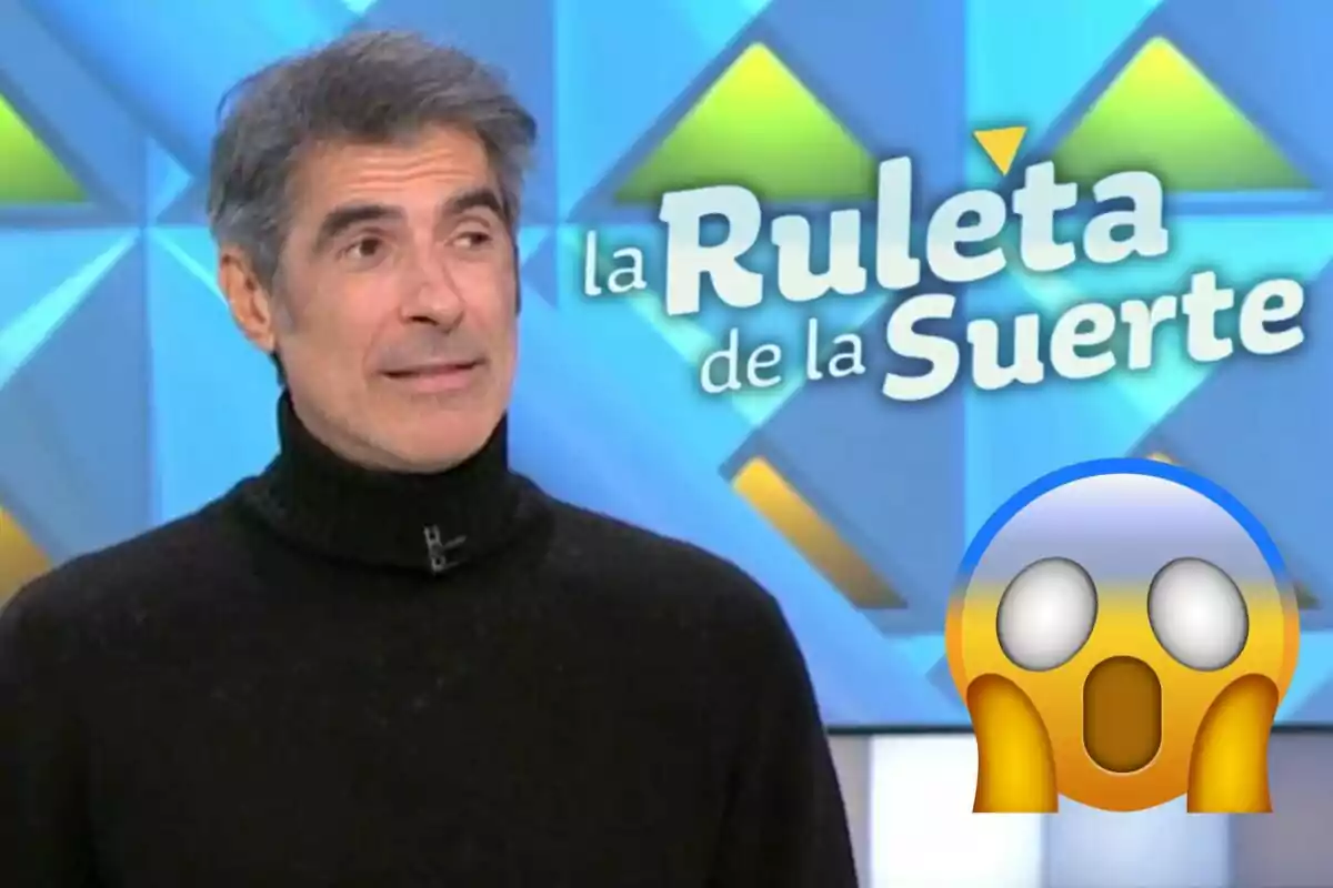 Jorge Fernández amb jersei negre apareix en un programa de televisió anomenat "La Ruleta de la Suerte" amb un emoji sorprès a la cantonada.