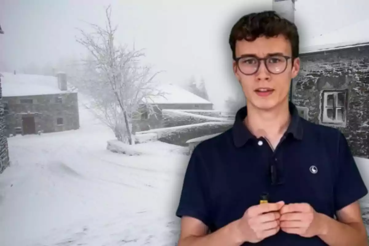 Un hombre con gafas y camisa oscura está frente a un paisaje nevado con casas de piedra y un árbol cubierto de nieve.