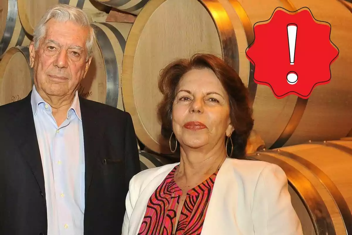 Mario Vargas Llosa i Patricia Llosa posant davant de barrils de fusta amb una icona d'advertència vermella a la cantonada superior dreta.