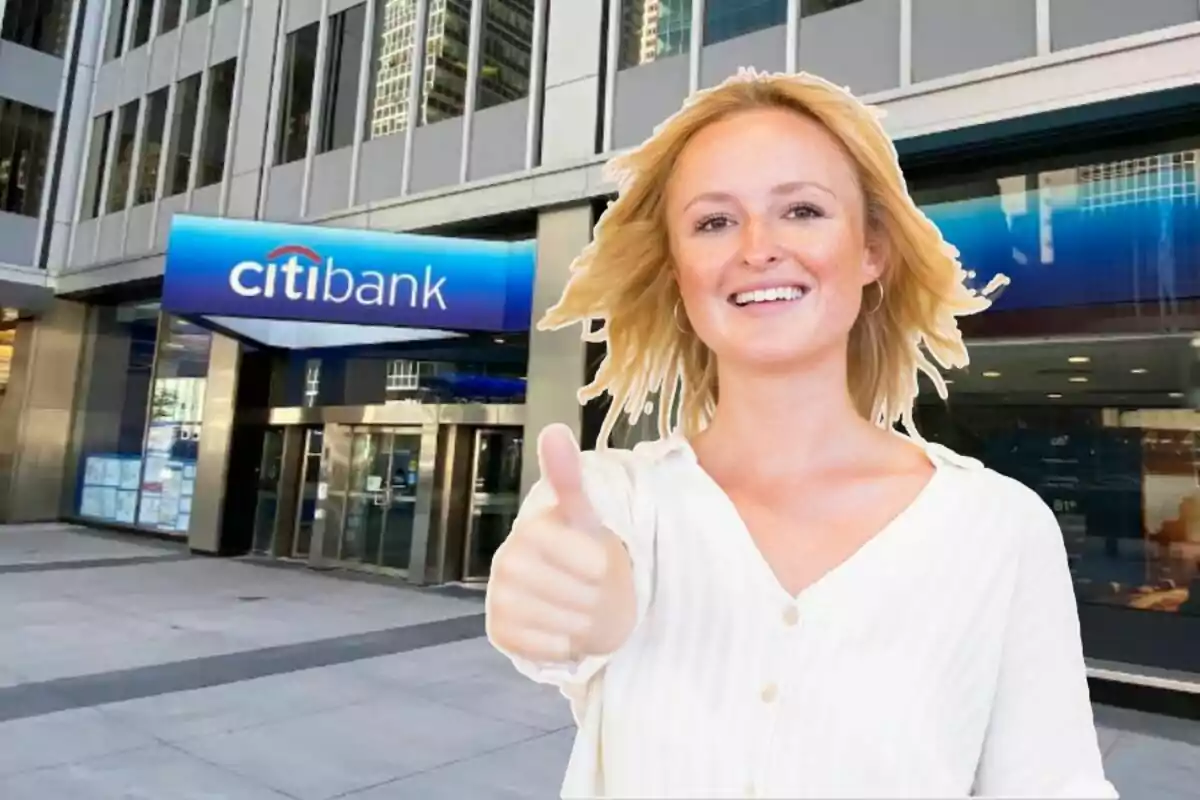 Una persona sonriente con el pulgar hacia arriba frente a un edificio de Citibank.