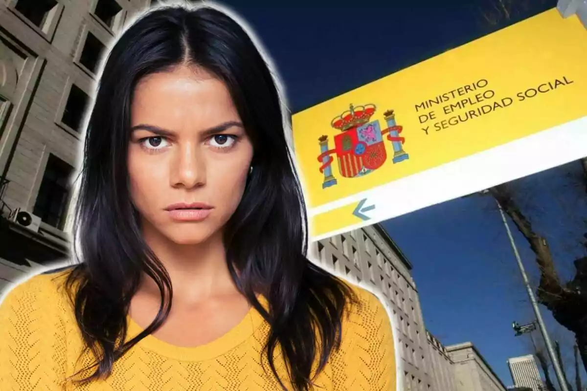 Una dona amb expressió seriosa davant d?un edifici i un cartell del Ministeri d?Ocupació i Seguretat Social d?Espanya.