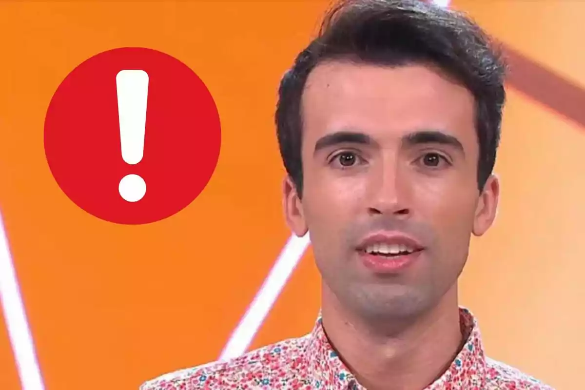 Bruno Vila amb camisa de colors davant d´un fons taronja amb una icona d´exclamació en un cercle vermell.