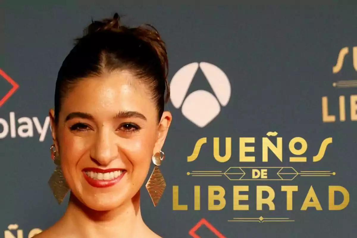 Candela Cruz somrient amb pendents grans davant d'un cartell que diu "Sueños de Libertad".