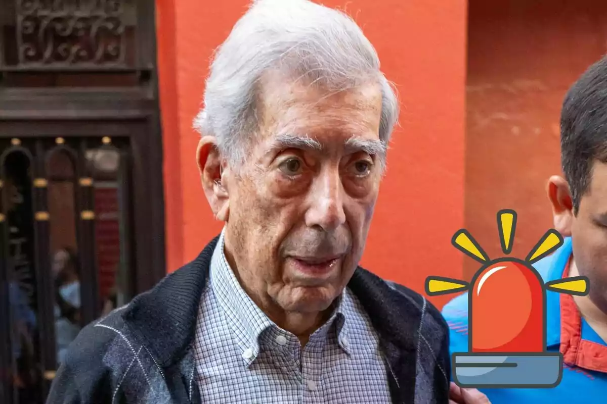 Mario Vargas Llosa amb cabell canós i expressió seriosa, acompanyat per una altra persona, amb una icona de sirena d'emergència superposada a la imatge.