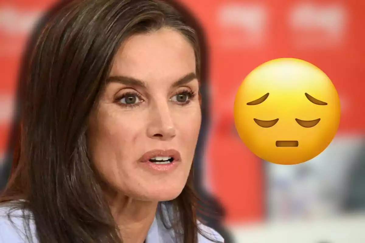 La reina Letícia amb expressió seriosa i un emoji de cara preocupada sobre fons vermell desenfocat