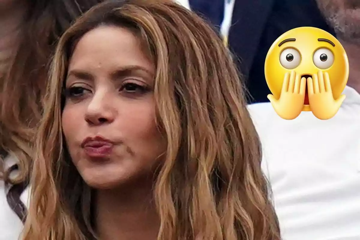 Shakira is making a gesture with her lips, while a surprised emoji is overlaid on the image.