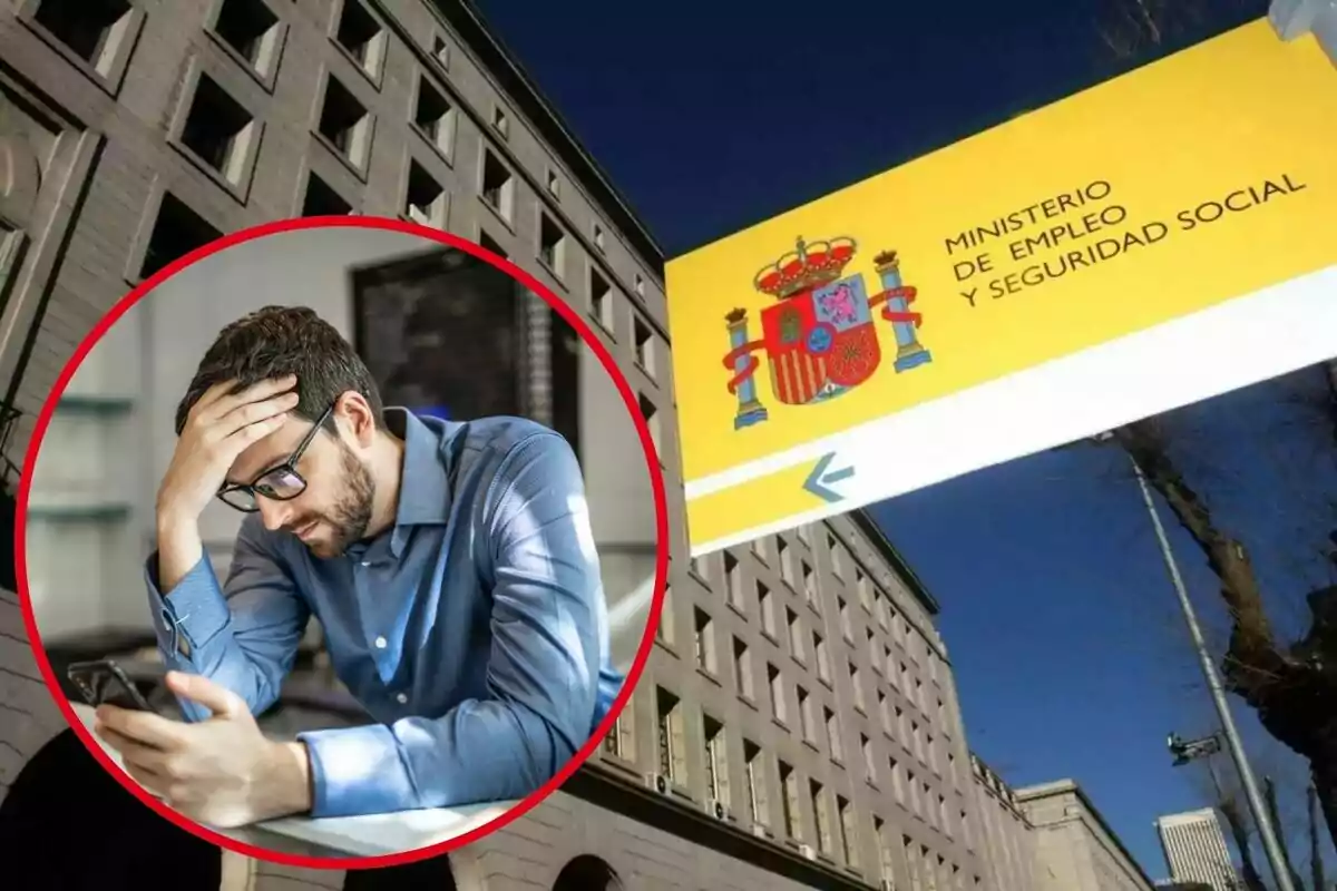 Un home amb ulleres i expressió preocupada mira el telèfon mòbil, amb un edifici del Ministeri d'Ocupació i Seguretat Social d'Espanya al fons.