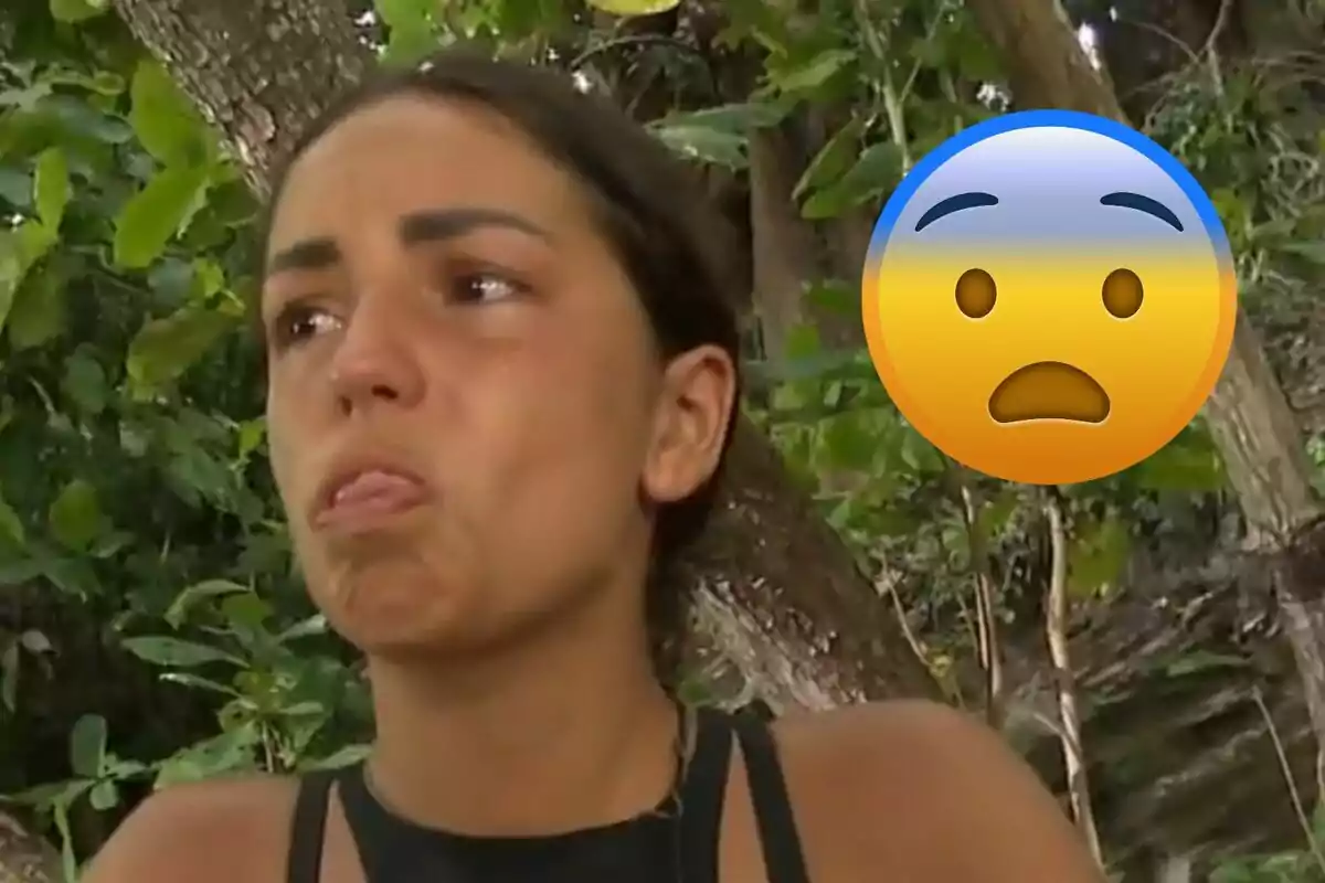 Anita con expresión triste y un emoji de cara preocupada sobre un fondo de vegetación