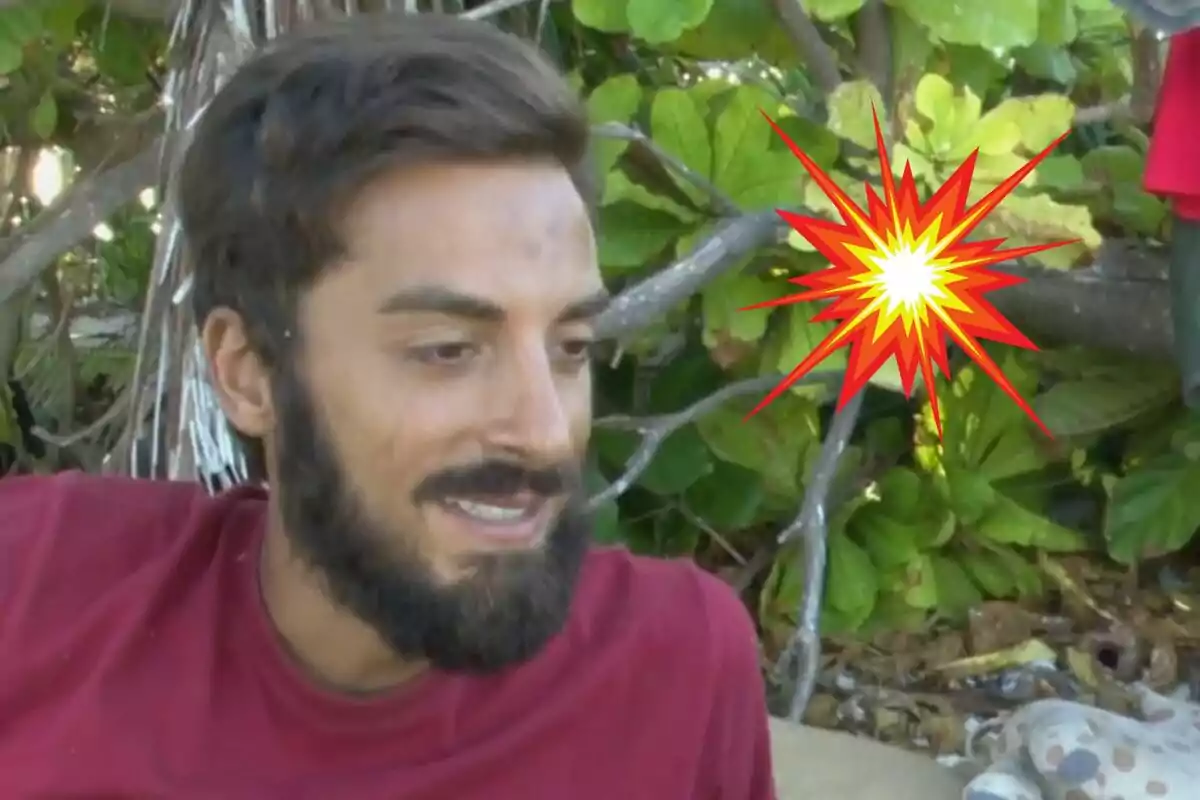 Borja González amb una samarreta vermella assegut a l’aire lliure amb un dibuix d’explosió de colors brillants sobre un fons de fulles verdes.